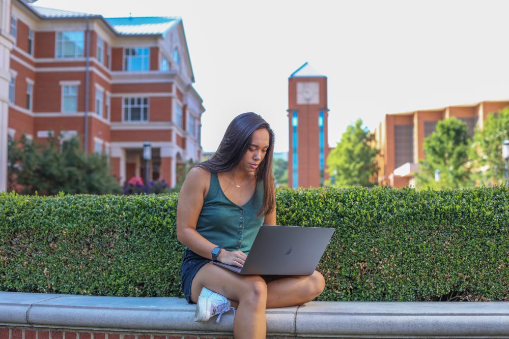 Student on campus reading a laptop